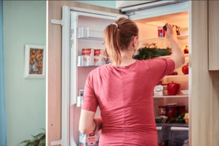 donna che mette il cibo in frigo